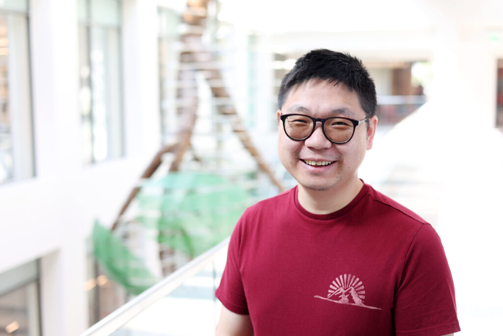 Headshot of Long Luo in a science building wearing a red shirt and glasses